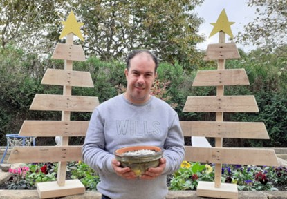 Tommy with one of his hand painted plant pots and recycled Christmas trees