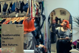 Inside a Brandon charity shop. Poster states: Sustainable fashion is the future