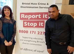 Brandon hate crime trainers standing next to a banner by Bristol Hate Crime and Discrimination Services banner
